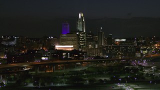 DX0002_173_031 - 5.7K stock footage aerial video fly away from the city's skyline at night, seen from river, Downtown Omaha, Nebraska