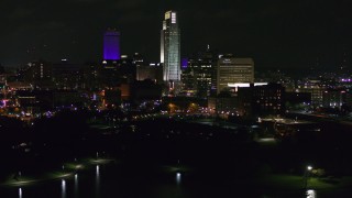 DX0002_173_049 - 5.7K aerial stock footage of slowly flying away from tall skyscrapers at night, Downtown Omaha, Nebraska