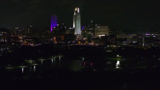 DX0002_173_050 - 5.7K aerial stock footage of a reverse view of tall skyscrapers at night, Downtown Omaha, Nebraska