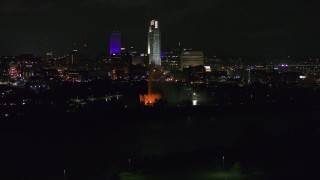 DX0002_173_053 - 5.7K aerial stock footage of towering skyscrapers behind the fountain lit up at night, Downtown Omaha, Nebraska