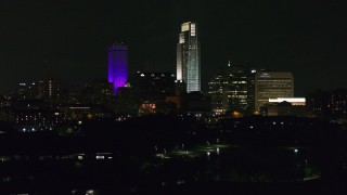 DX0002_173_061 - 5.7K aerial stock footage descending away from the city's skyscrapers seen from the park at night, Downtown Omaha, Nebraska