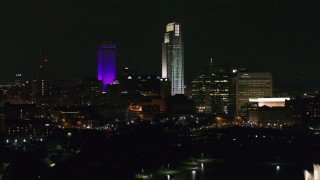 DX0002_173_062 - 5.7K aerial stock footage ascend toward the city's skyscrapers from the park at night, Downtown Omaha, Nebraska