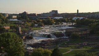 DX0002_176_005 - 5.7K aerial stock footage of orbiting the waterfalls at Falls Park at sunset in Sioux Falls, South Dakota