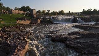 DX0002_176_009 - 5.7K aerial stock footage of low stationary view of waterfalls at sunset in Sioux Falls, South Dakota