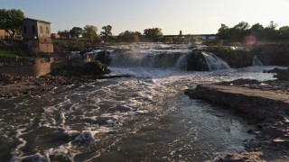 DX0002_176_010 - 5.7K aerial stock footage of flying low over waterfalls at sunset in Sioux Falls, South Dakota