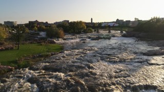 DX0002_176_011 - 5.7K aerial stock footage of a reverse view of waterfalls at sunset in Sioux Falls, South Dakota