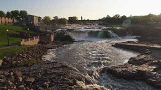 DX0002_176_012 - 5.7K aerial stock footage of flying by the waterfalls at sunset in Sioux Falls, South Dakota