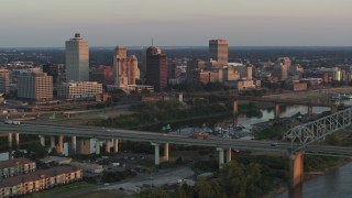 DX0002_181_012 - 5.7K aerial stock footage of passing the city's skyline behind the bridge and the river at sunset, Downtown Memphis, Tennessee