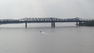 DX0002_183_021 - 5.7K aerial stock footage of a boat speeding across the Mississippi River toward Harahan Bridge, Memphis, Tennessee