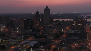DX0002_187_018 - 5.7K aerial stock footage of the 100 North Main office tower near the bridge at twilight, Downtown Memphis, Tennessee