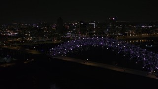 DX0002_187_034 - 5.7K aerial stock footage of flying by the bridge with purple lights and the Downtown Memphis skyline, Tennessee