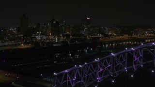DX0002_187_035 - 5.7K aerial stock footage of the downtown skyline, reveal the bridge with purple lights at night, Downtown Memphis, Tennessee