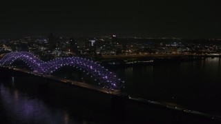 DX0002_187_038 - 5.7K aerial stock footage flying by the bridge with colorful lights with a view of the skyline at night, Downtown Memphis, Tennessee