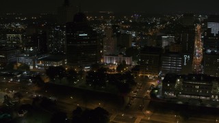 DX0002_187_075 - 5.7K aerial stock footage of Raymond James Tower and nearby buildings at nighttime, Downtown Memphis, Tennessee