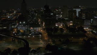 DX0002_187_076 - 5.7K aerial stock footage fly away from Raymond James Tower and nearby buildings at nighttime, Downtown Memphis, Tennessee