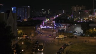 DX0002_188_021 - 5.7K aerial stock footage of flying by trees and building to reveal the Beale Street sign at nighttime, Downtown Memphis, Tennessee