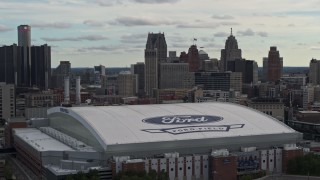 DX0002_191_028 - 5.7K aerial stock footage focus on downtown skyline and descend by Ford Field, Downtown Detroit, Michigan