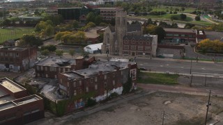 DX0002_192_014 - 5.7K aerial stock footage orbit an abandoned building and reveal a church at sunset, Detroit, Michigan