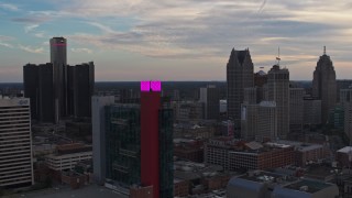 DX0002_192_035 - 5.7K aerial stock footage of passing by a hotel to focus on skyscrapers at sunset, Downtown Detroit, Michigan