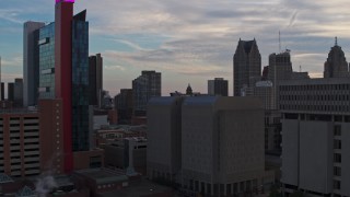 DX0002_192_038 - 5.7K aerial stock footage descend past skyscrapers at sunset to reveal a hotel, Downtown Detroit, Michigan