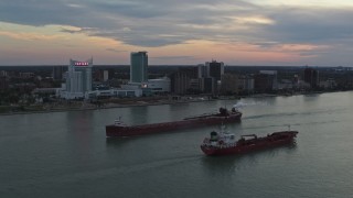 DX0002_192_045 - 5.7K aerial stock footage of oil tankers passing on the Detroit River near skyline of Windsor, Ontario, Canada, sunset