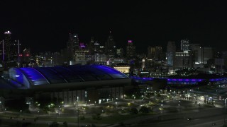 DX0002_193_045 - 5.7K aerial stock footage ascend past stadiums for view of skyline at night, Downtown Detroit, Michigan
