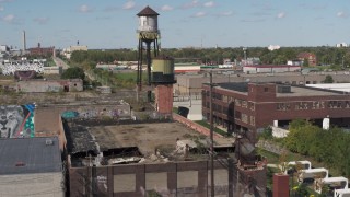 DX0002_194_048 - 5.7K aerial stock footage of orbiting a water tower atop an abandoned brick building in Detroit, Michigan