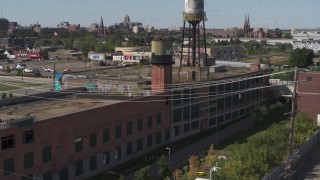 DX0002_194_049 - 5.7K aerial stock footage of orbiting an abandoned brick building with a water tower on the roof in Detroit, Michigan