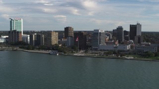 DX0002_196_007 - 5.7K aerial stock footage of orbiting office buildings and Canadian flag by the river in Windsor, Ontario, Canada
