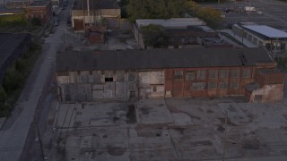 DX0002_197_016 - 5.7K aerial stock footage descend by abandoned factory building at sunset, Detroit, Michigan