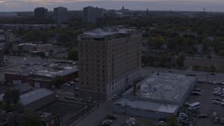 DX0002_197_023 - 5.7K aerial stock footage of flying away from an apartment building at sunset, Detroit, Michigan