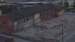 DX0002_197_051 - 5.7K aerial stock footage ascend away from an abandoned brick building at sunset, Detroit, Michigan