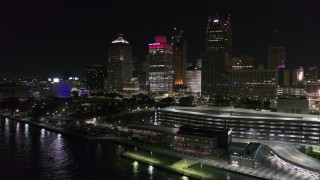 DX0002_199_022 - 5.7K aerial stock footage of Hart Plaza by tall skyscrapers at night, seen from the river, Downtown Detroit, Michigan