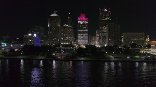 DX0002_199_025 - 5.7K aerial stock footage descend by riverfront Hart Plaza, focus on tall skyscrapers at night, Downtown Detroit, Michigan