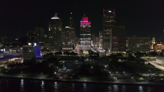 DX0002_199_026 - 5.7K aerial stock footage ascend by riverfront Hart Plaza, focus on tall skyscrapers at night, Downtown Detroit, Michigan