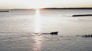 DX0002_204_013 - 5.7K aerial stock footage of a stationary view of Lake Erie as a rowboat and speedboat pass at sunset, Buffalo, New York