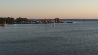 DX0002_204_015 - 5.7K aerial stock footage flying toward a sailboat on Lake Erie near lighthouse at sunset, Buffalo, New York