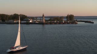 DX0002_204_016 - 5.7K aerial stock footage flying around a sailboat on Lake Erie toward lighthouse at sunset, Buffalo, New York