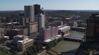 DX0002_206_006 - 5.7K aerial stock footage ascend over river for view of hotel near the city's skyline, Downtown Rochester, New York