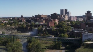 DX0002_206_027 - 5.7K aerial stock footage of the city's skyline behind waterfalls on the river, Downtown Rochester, New York