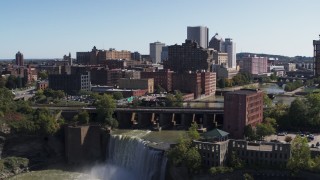 DX0002_206_028 - 5.7K aerial stock footage approach the city's skyline behind waterfalls on the river, Downtown Rochester, New York