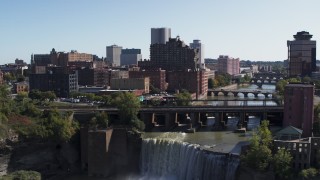 DX0002_206_032 - 5.7K aerial stock footage fly over falls and bridges to toward the city's skyline, Downtown Rochester, New York