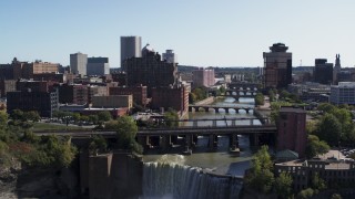 DX0002_207_003 - 5.7K aerial stock footage ascend over falls for view of river bridges and skyline Downtown Rochester, New York