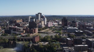 DX0002_207_007 - 5.7K aerial stock footage focus on skyline by river bridges while flying near waterfall, Downtown Rochester, New York