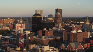 DX0002_209_027 - 5.7K aerial stock footage of flying by office buildings and a radio tower at sunset, Downtown Rochester, New York