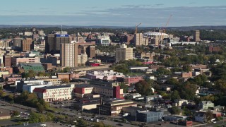 DX0002_213_012 - 5.7K aerial stock footage of Carrier Dome stadium behind office buildings in Downtown Syracuse, New York