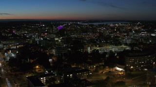 DX0002_215_003 - 5.7K aerial stock footage of a wide view of city buildings lit up for the evening in Downtown Syracuse at twilight, New York