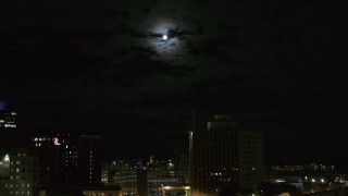 DX0002_215_042 - 5.7K aerial stock footage of the moon above the 500 Building at night, reveal apartment building, Downtown Syracuse, New York