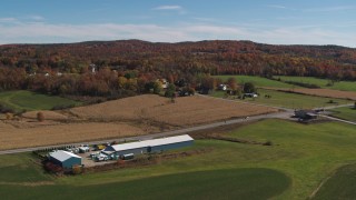 DX0002_217_011 - 5.7K aerial stock footage descend and flyby a country road beside a small town in autumn, Orwell, Vermont