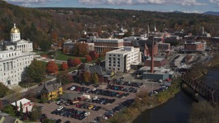 DX0002_218_019 - 5.7K aerial stock footage ascend over river to reveal government offices and smoke stack by the river, Montpelier, Vermont